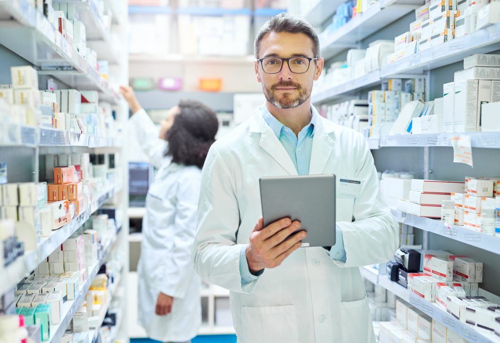 a male pharmacist in the storeroom surrounded by loads of drugs