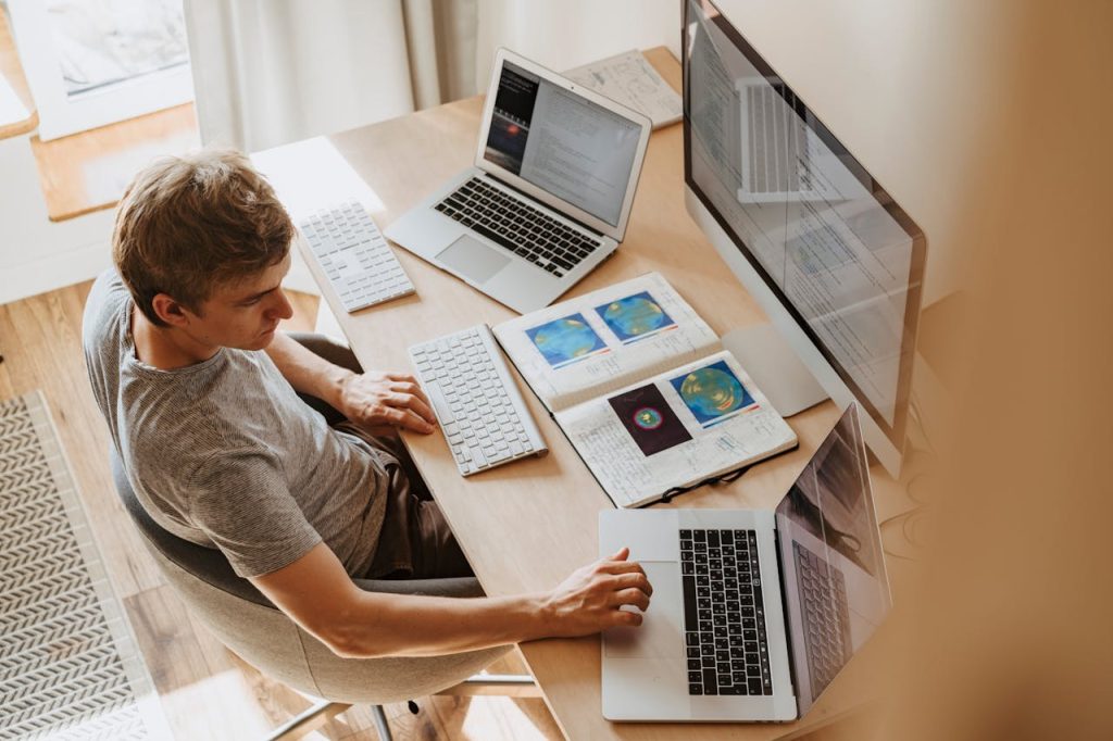 a man with an proposterous amount of laptops and keyboards, doing some work, seemingly analysing the earth's temperature