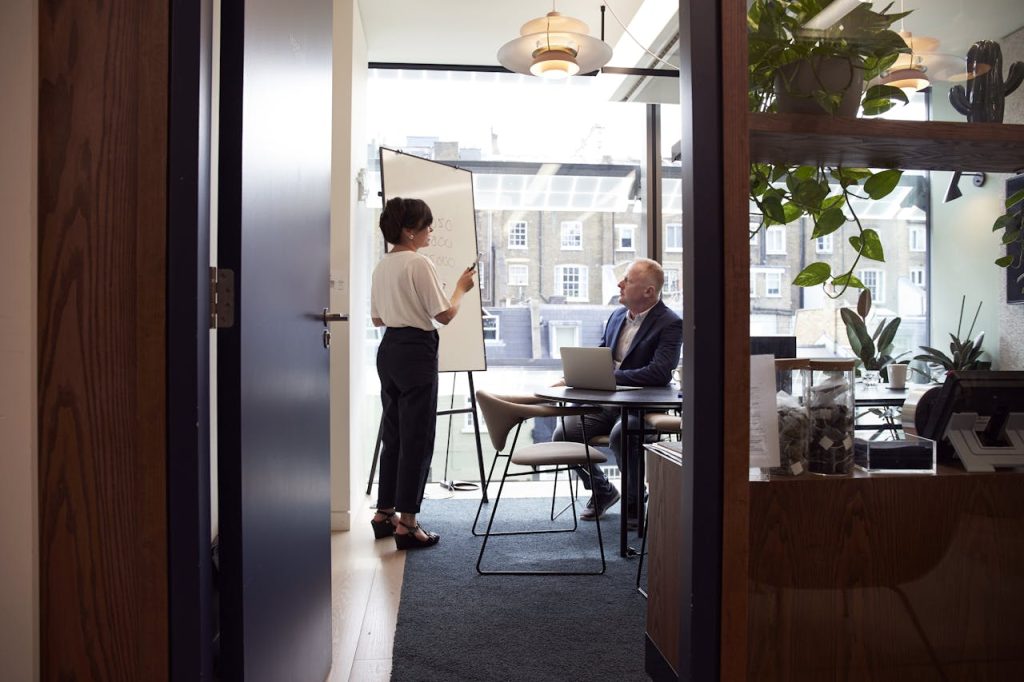 two individuals having a private meeting about numbers, there are two massive jars full of teabags in the foreground