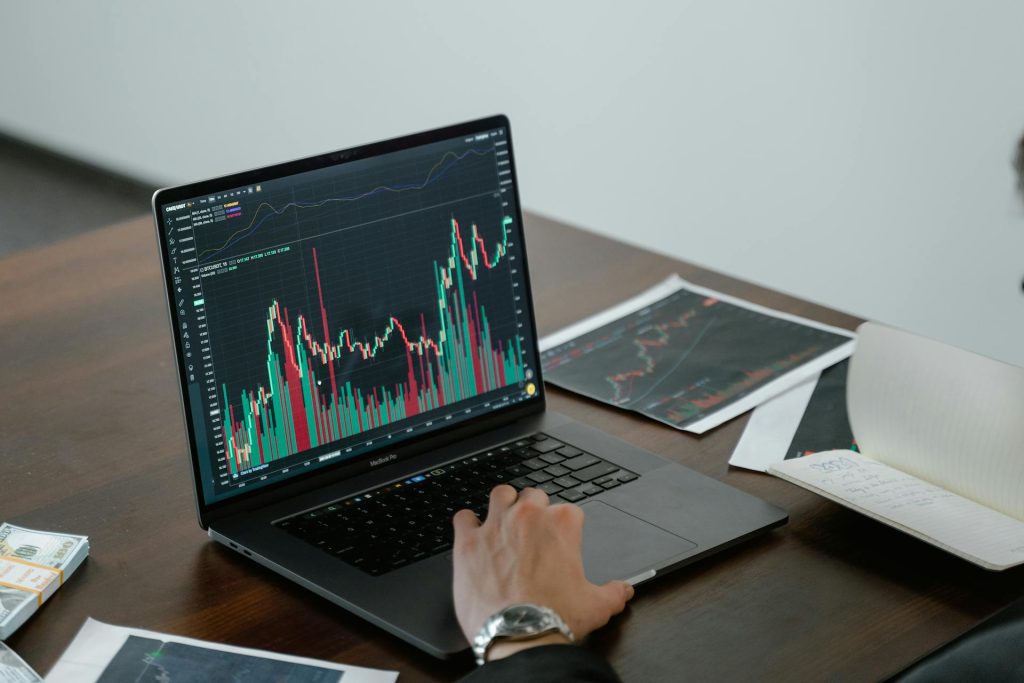 a person looking at some graphs on a laptop, he also has some printed out in dark mode on some paper. the paper is noticeably soaked and warped by how much blank ink was applied by the printer